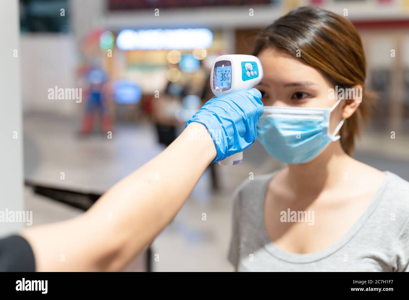 Medición de la temperatura corporal, la joven asiática es revisada por termómetro digital infrarrojo antes de entrar al edificio o restaurante en el exterior coronavirus Foto de stock