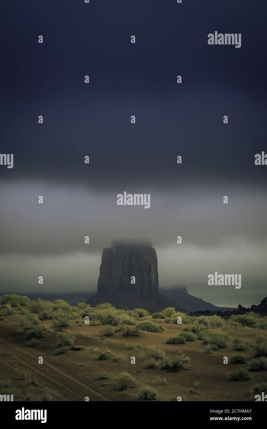 Tiro vertical de una formación de roca en el medio de un paisaje desierto cubierto de niebla Foto de stock