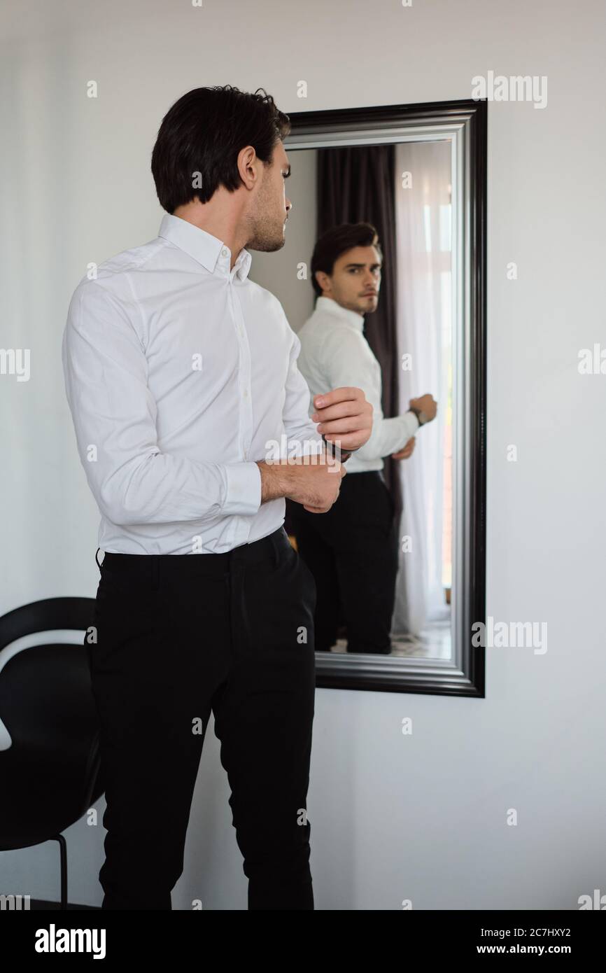 cortador importar Física Joven guapo hombre morena con camisa blanca y pantalón negro, con un espejo  de ensueño en casa Fotografía de stock - Alamy