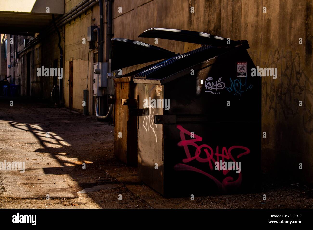 Graffiti etiquetó los cubos de basura en un callejón. Se encuentra en el centro de Waco. Foto de stock