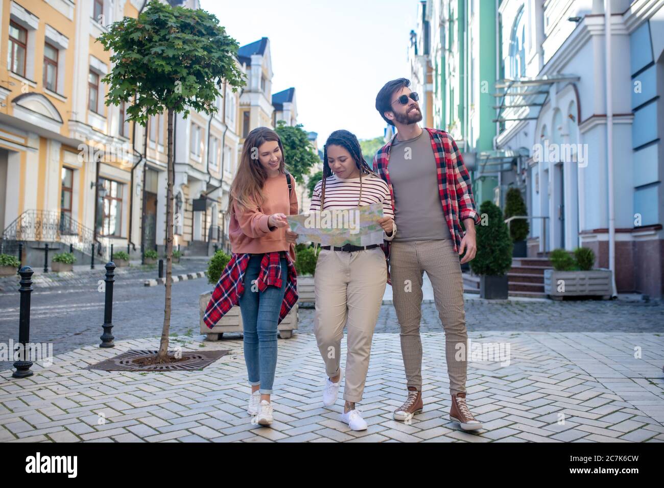 Dos chicas con mapa y un chico zapatillas de deporte caminando la calle Fotografía de stock - Alamy