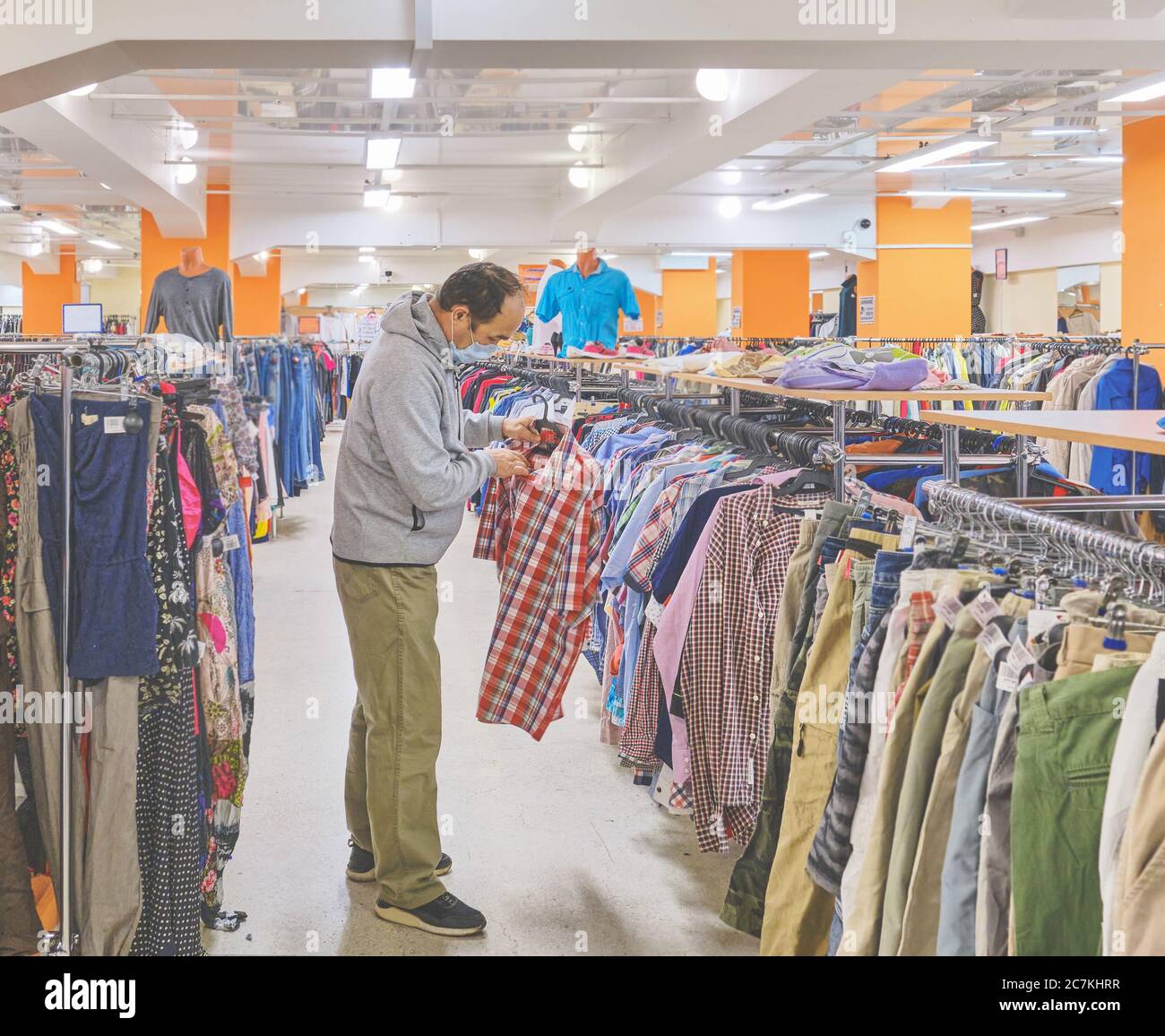 Hombre maduro en máscara escogiendo ropa en la tienda de segunda mano.  Consumo consciente, un nuevo concepto normal Fotografía de stock - Alamy