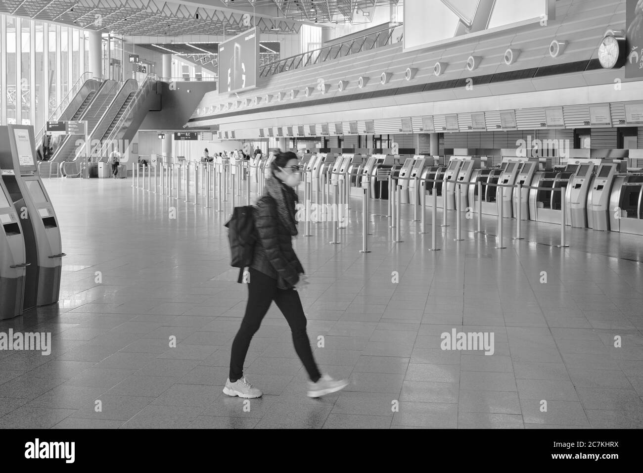 Un joven viajero con máscara cruza la terminal de salida casi vacía de la Terminal 1 del aeropuerto de Frankfurt durante el cierre general en Alemania debido a la pandemia de corona. Foto de stock