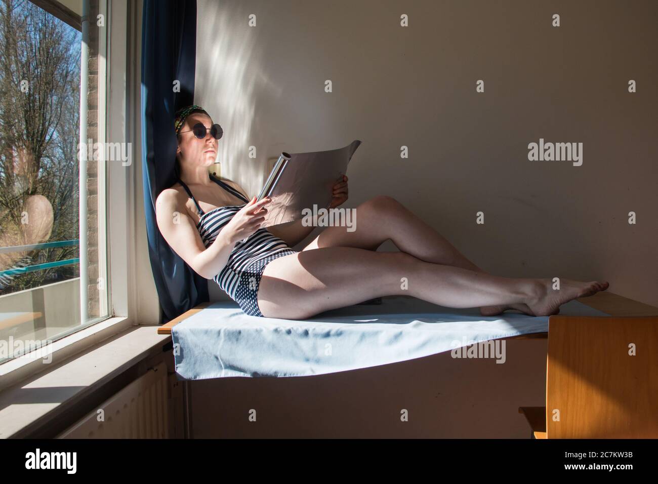 Joven estudiante tomando el sol en un escritorio en la ventana durante el cierre Foto de stock
