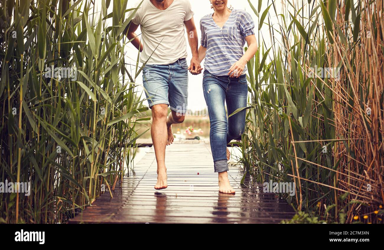 Pareja corriendo en la lluvia.Feliz hombre y mujer en el estanque en el día de lluvia juntos. Foto de stock