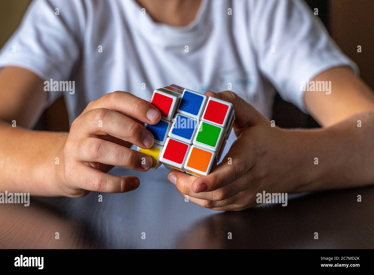 Manos infantiles tratando de resolver el cubo de Rubik Foto de stock