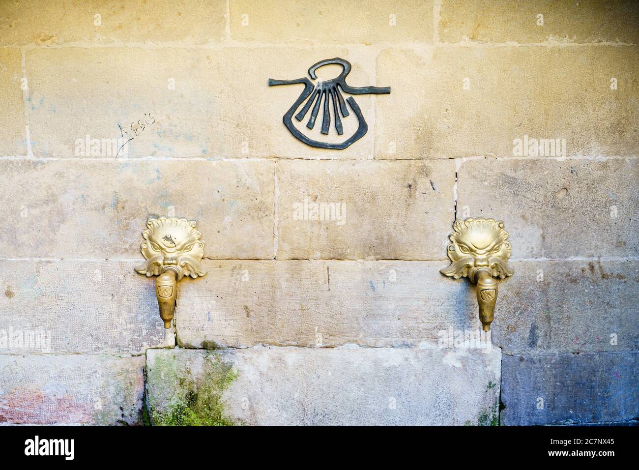 Hermoso tiro de Pilgrim Fuente dos golpecitos de león de oro y.. símbolo de concha de vieira negra en una pared de piedra Foto de stock