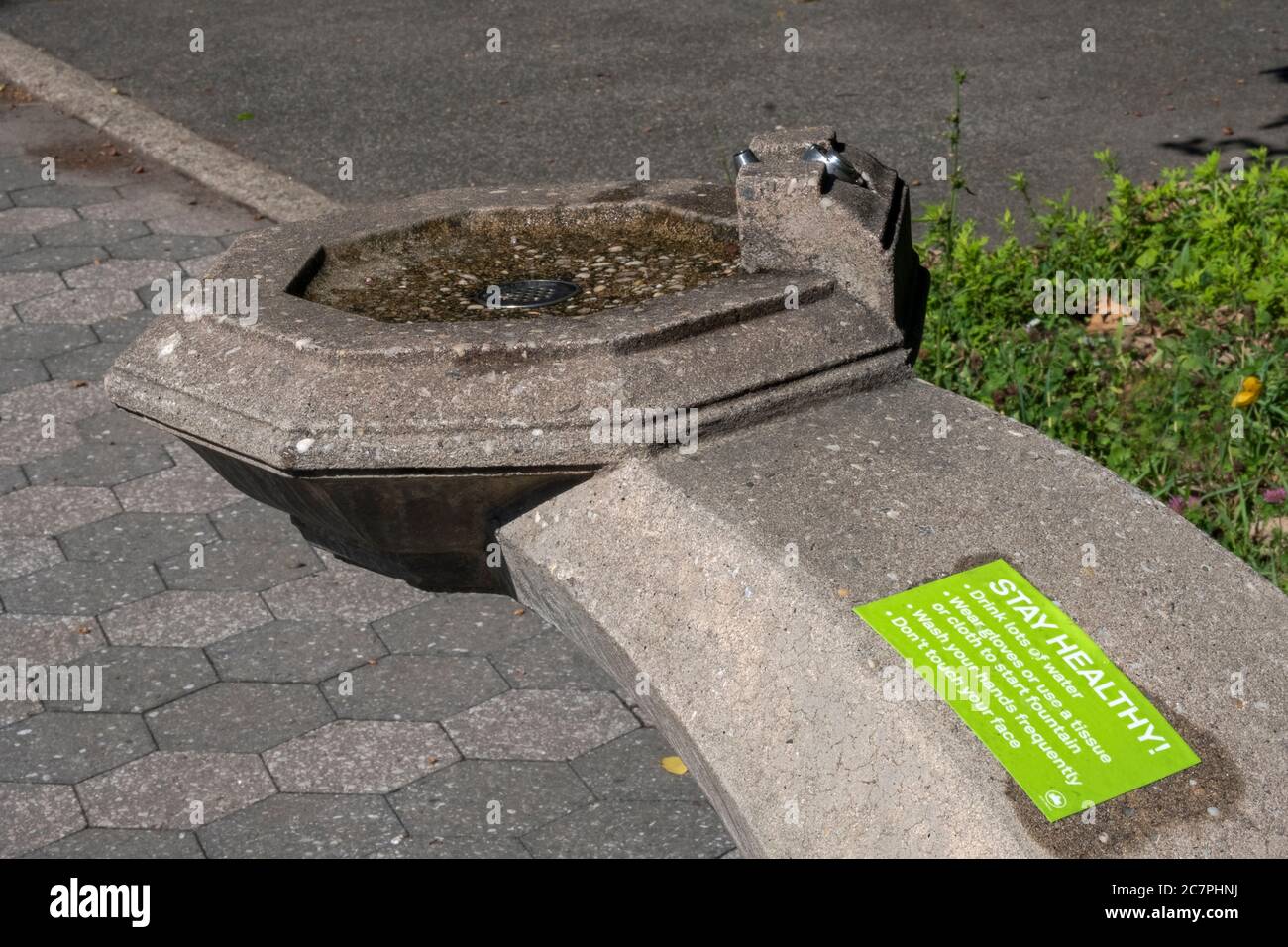 Un signo en una fuente de agua que aboga por un comportamiento saludable durante la pandemia del coronavirus. En Flushing, Queens, Nueva York. Foto de stock