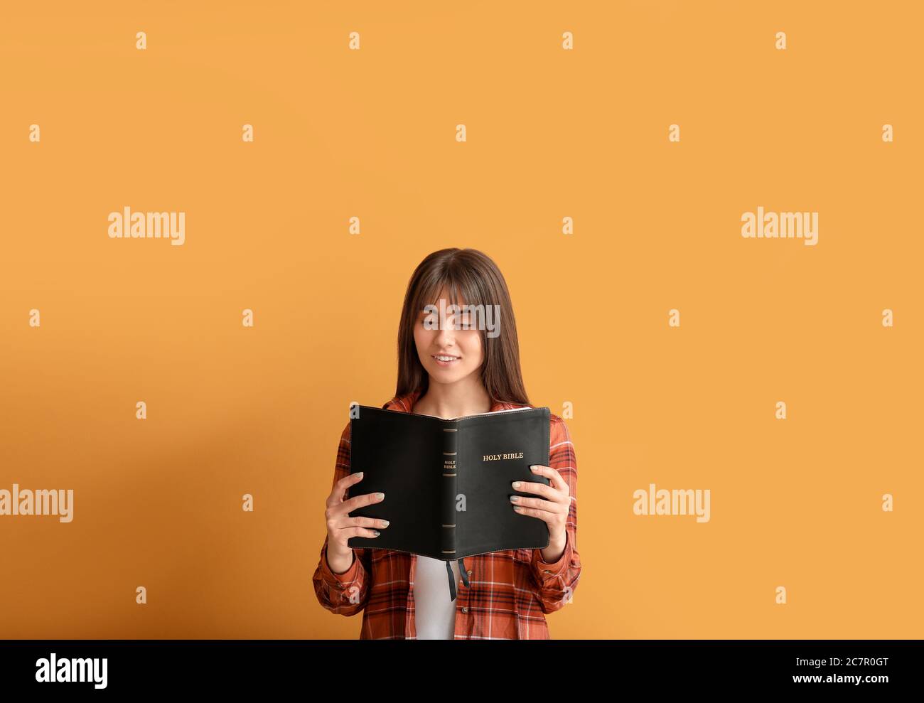 Mujer joven con Biblia sobre fondo de color Foto de stock