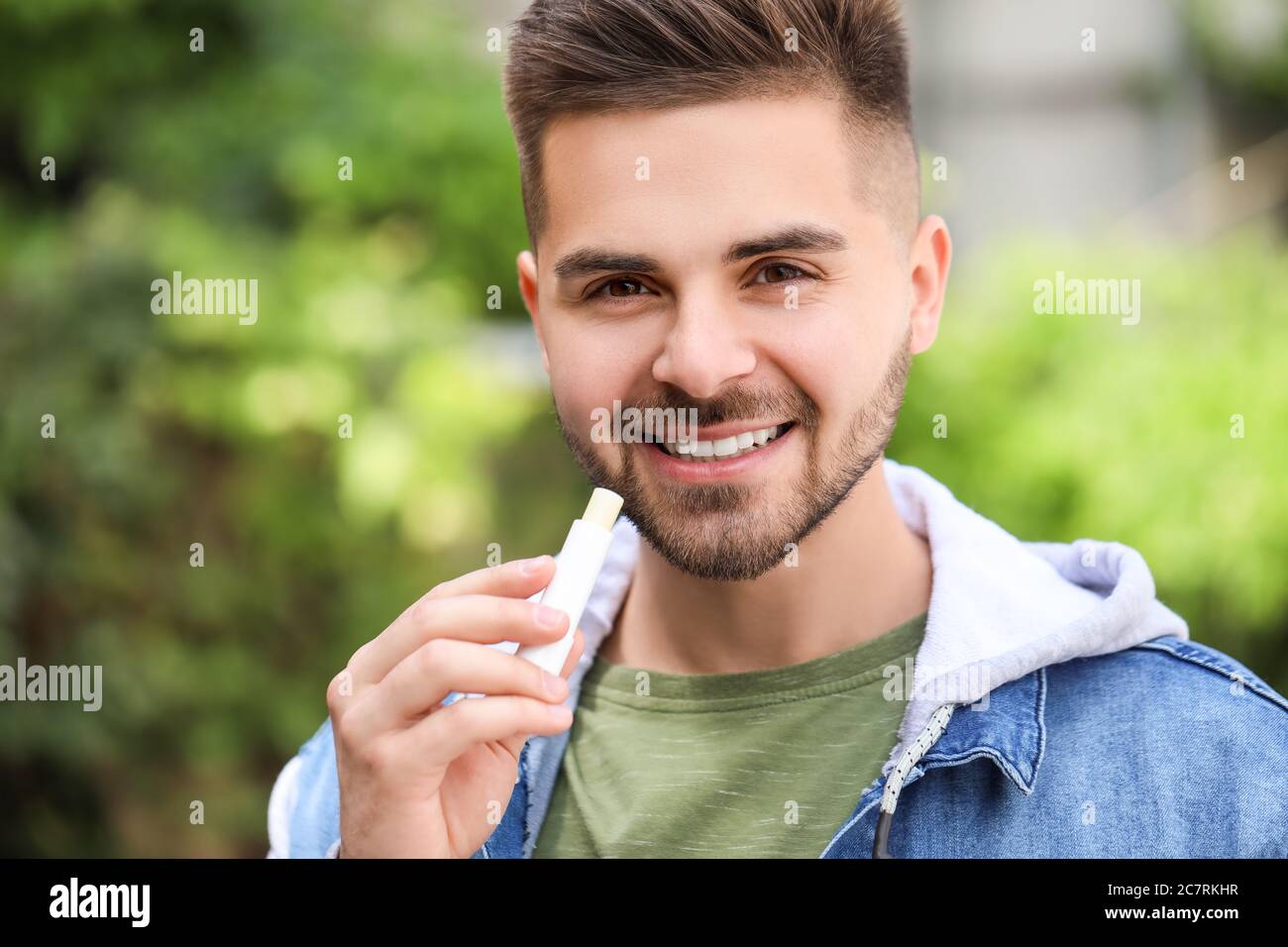 Hombre joven guapo con bálsamo labial al aire libre Foto de stock
