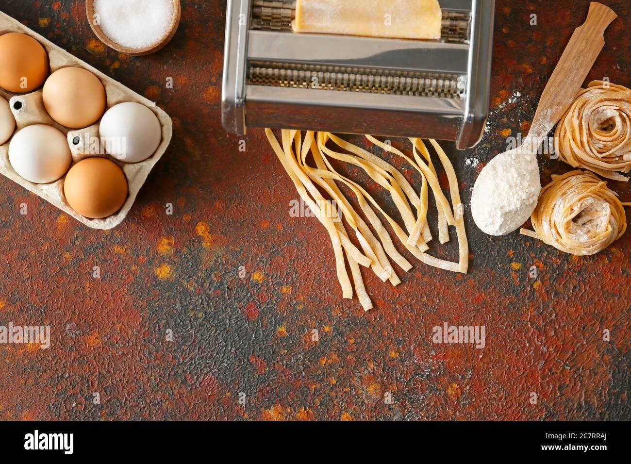 Máquina de pasta con ingredientes sobre fondo de color Foto de stock