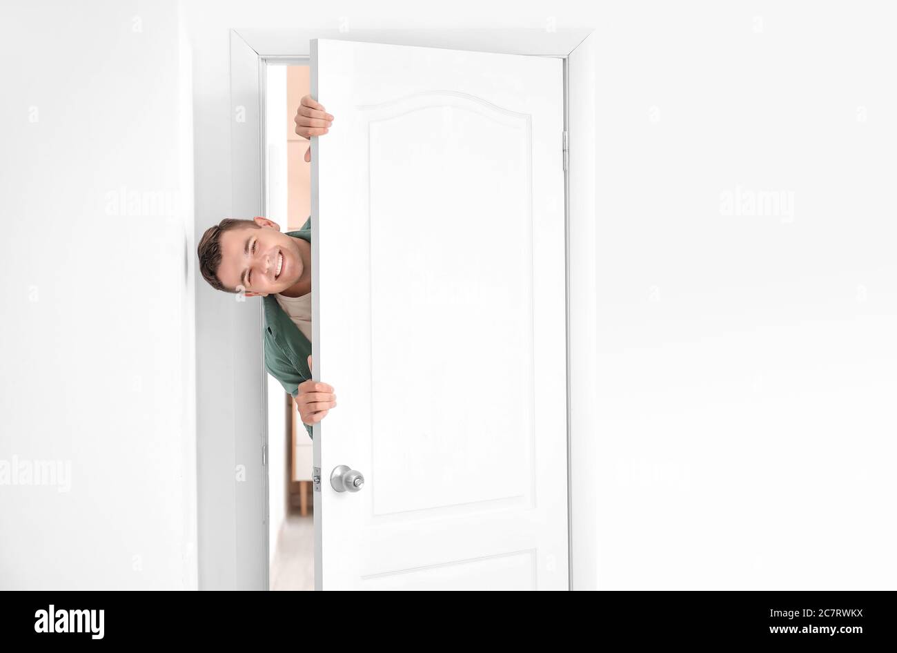 Hombre curioso mirando por la puerta Fotografía de stock - Alamy
