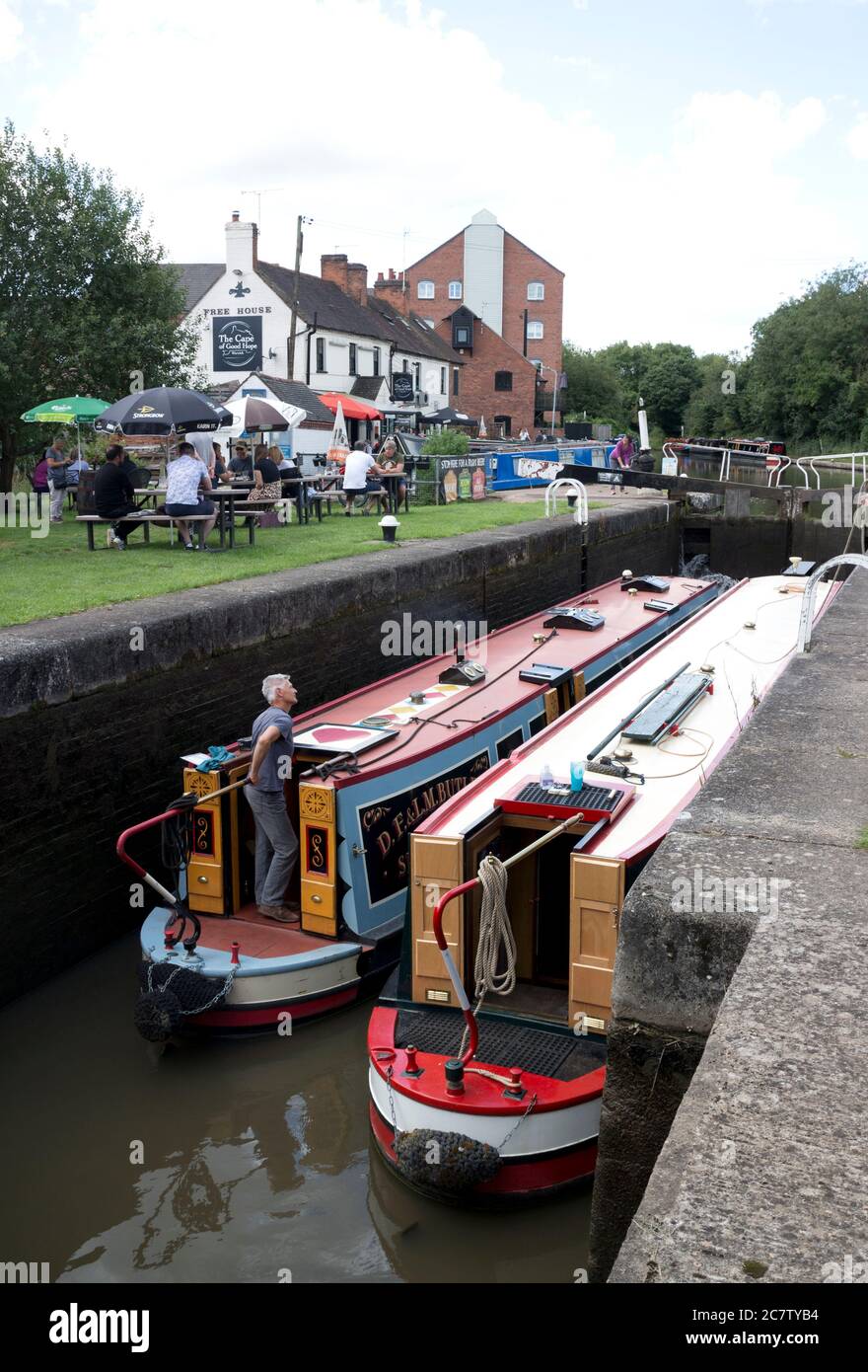 Barcos estrechos en Warwick Top Lock con gente fuera del Cape of Good Hope Pub durante la relajación de la cerradura Covid-19, Warwick, Reino Unido. 19 de julio de 2020. Foto de stock