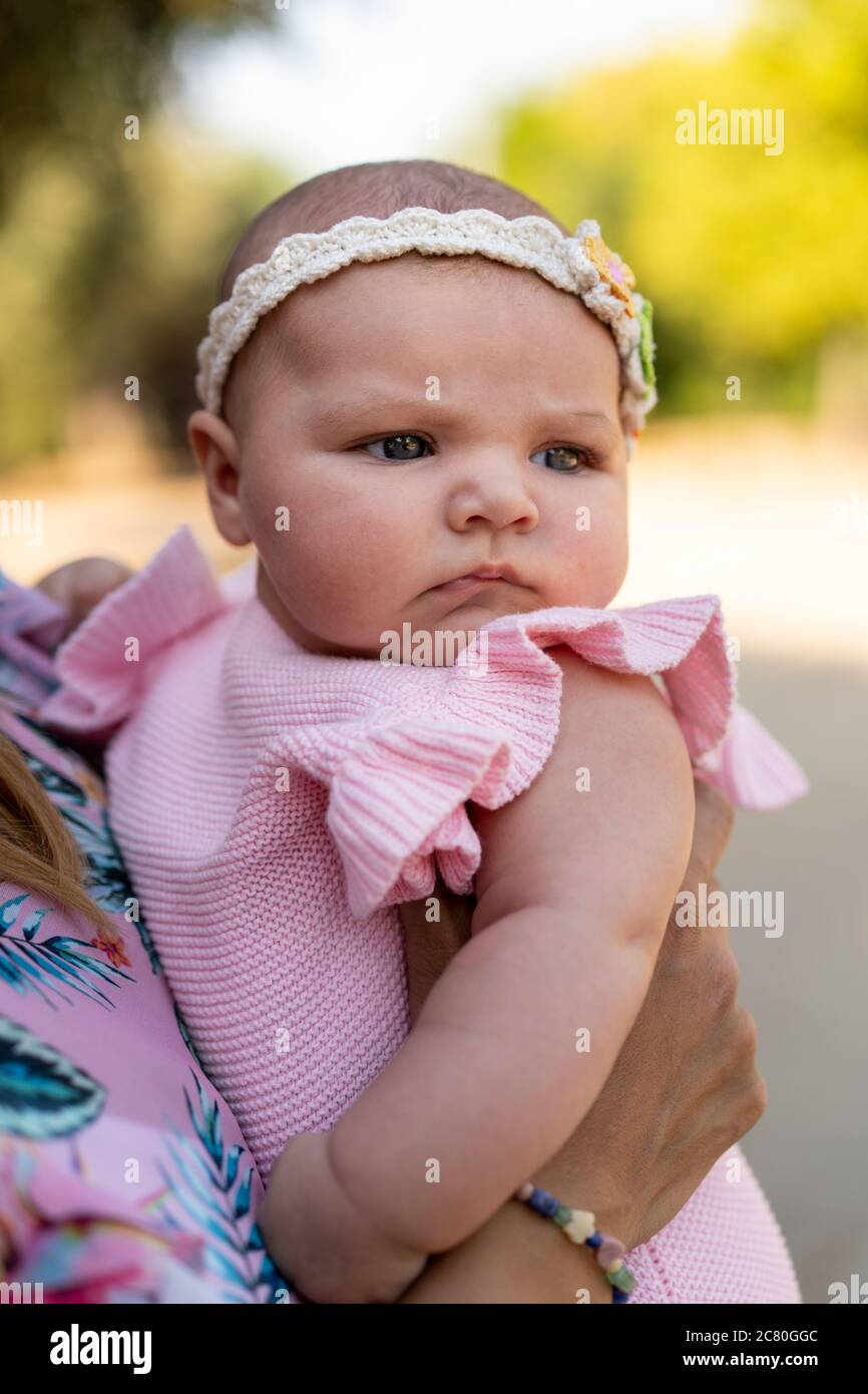 Bebé recién nacido con ropa de punto rosa y una cabeza accesorio en los  brazos de la mujer Fotografía de stock - Alamy