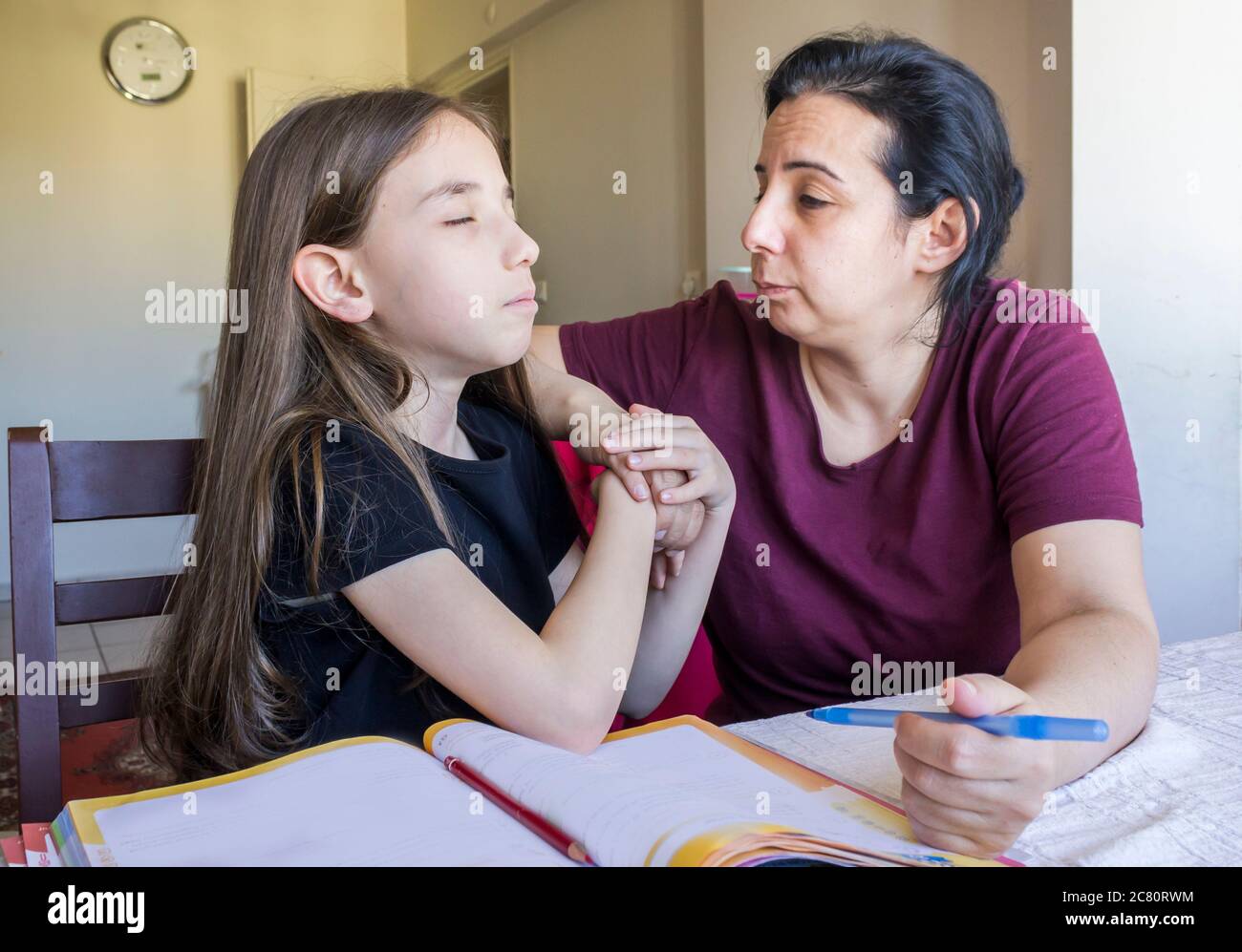 La estudiante de primaria hace su tarea con su madre. Ella hace sus propias tareas a través de tabletas en casa debido a que las escuelas están de vacaciones Foto de stock