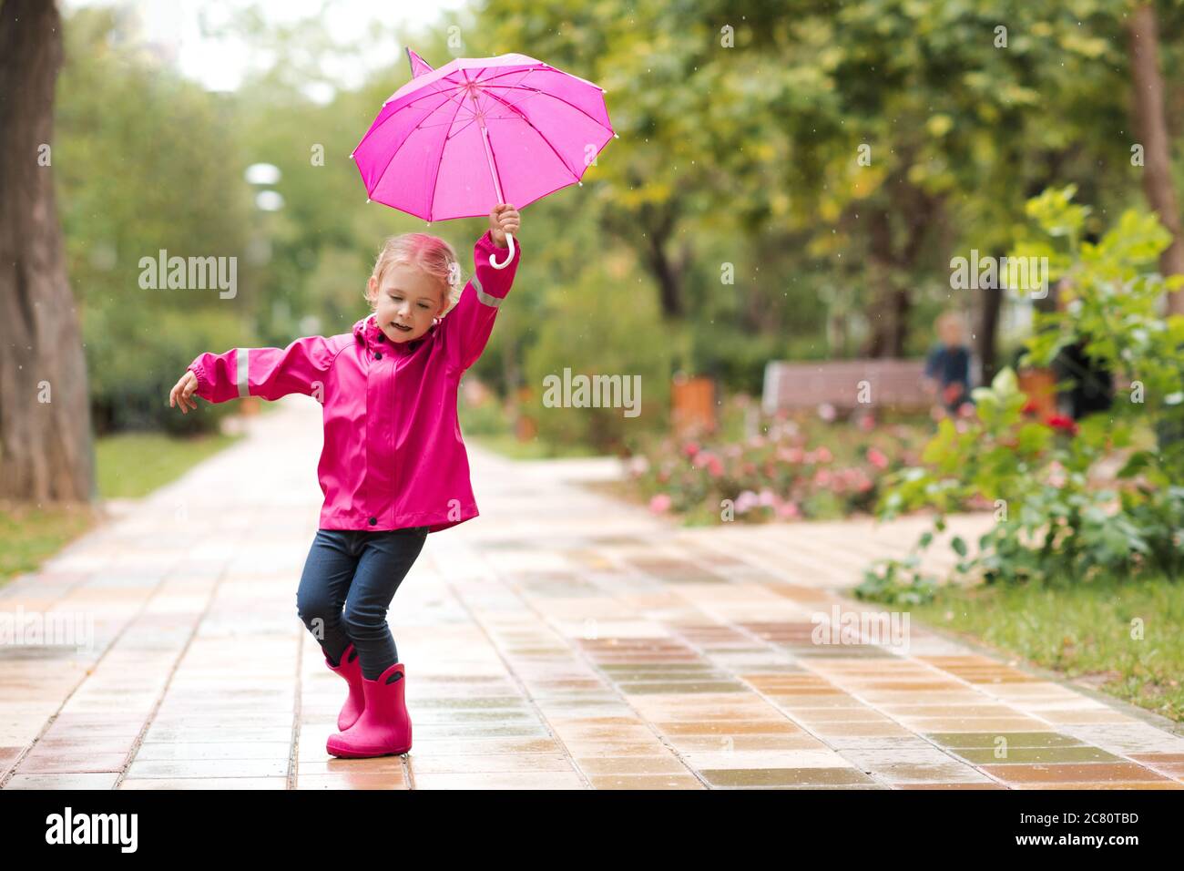 Niño niña de 2-3 años caminando en charco en el parque sosteniendo paraguas  rosa con botas impermeables al aire libre. La infancia. Temporada de otoño  Fotografía de stock - Alamy