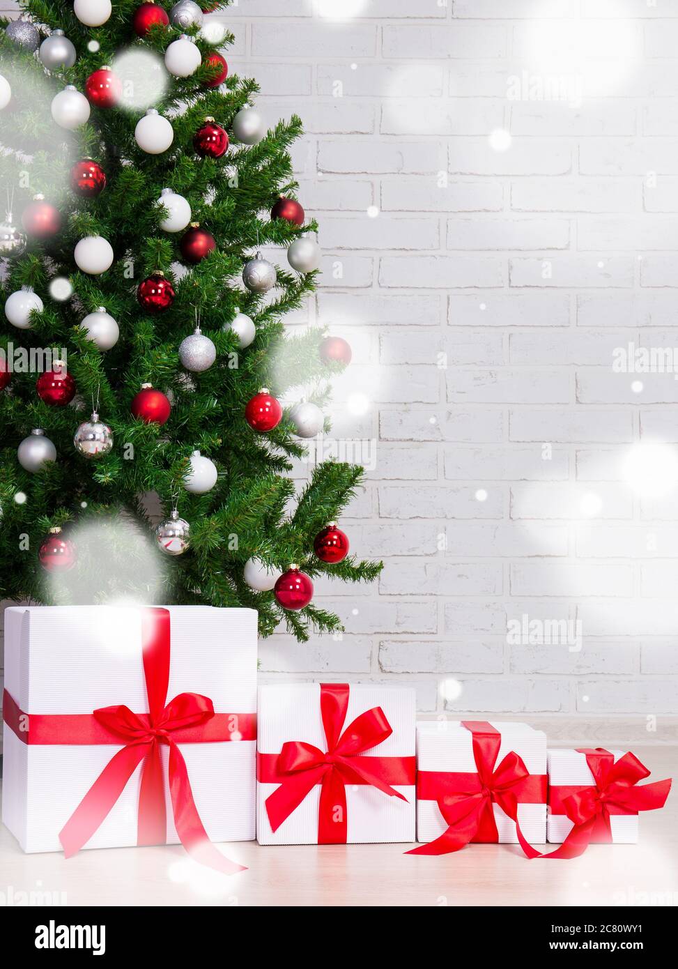 fondo de navidad - cajas de regalo bajo árbol de navidad decorado sobre  pared de ladrillo y copos de nieve voladores Fotografía de stock - Alamy