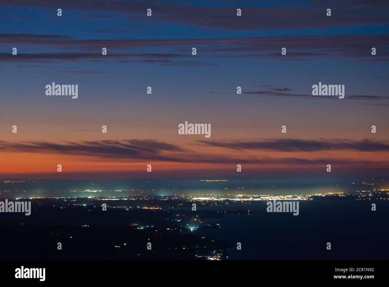 Zoom shot, cielo colorido después de la puesta de sol y las luces de la ciudad de Puerto Varas Foto de stock