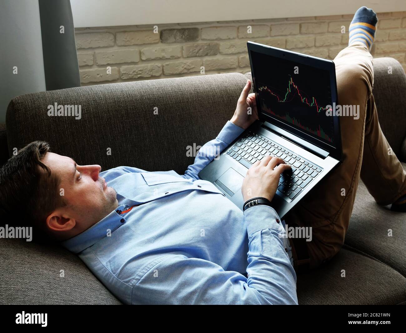 Un hombre en casa está analizando el comercio en un intercambio en línea. Foto de stock