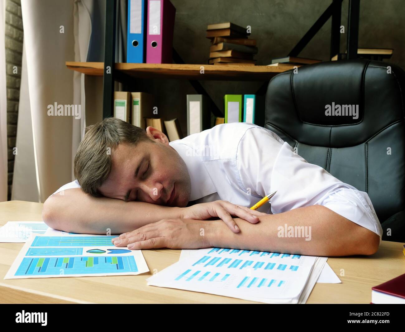 Un empleado cansado duerme en la mesa. Síndrome de fatiga crónica. Foto de stock