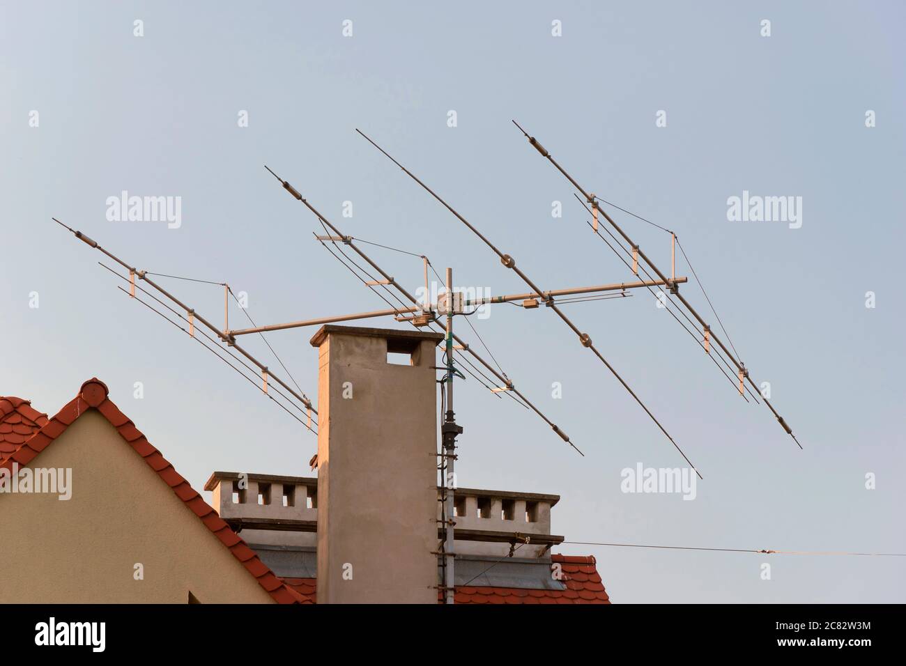 Antena de TV en el techo de la casa. Tecnología de emisión de televisión y  radio en la azotea. Receptor de señal. Torre de los medios de transmisión.  Techado residencial Fotografía de