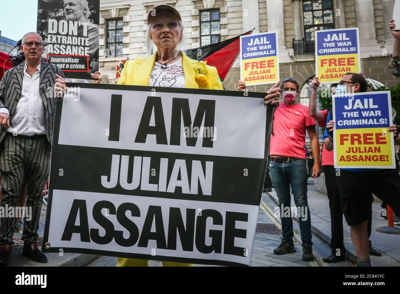Londres, Reino Unido, 21 de julio de 2020. Dame Vivienne Westwood está sosteniendo la bandera "Yo soy Julian Assange" en su protesta frente a la Corte Penal Central de Old Bailey, en protesta por la extradición de Julian Assange por los Estados Unidos. Westwood está vestido con un traje de pantalón amarillo, que enfigura la metáfora de la mina de carbón de Canarias, para ilustrar que Assange está siendo sacrificado. Más tarde se presenta frente al Viejo Bailey con su mensaje. Crédito: Imageplotter/Alamy Live News Foto de stock