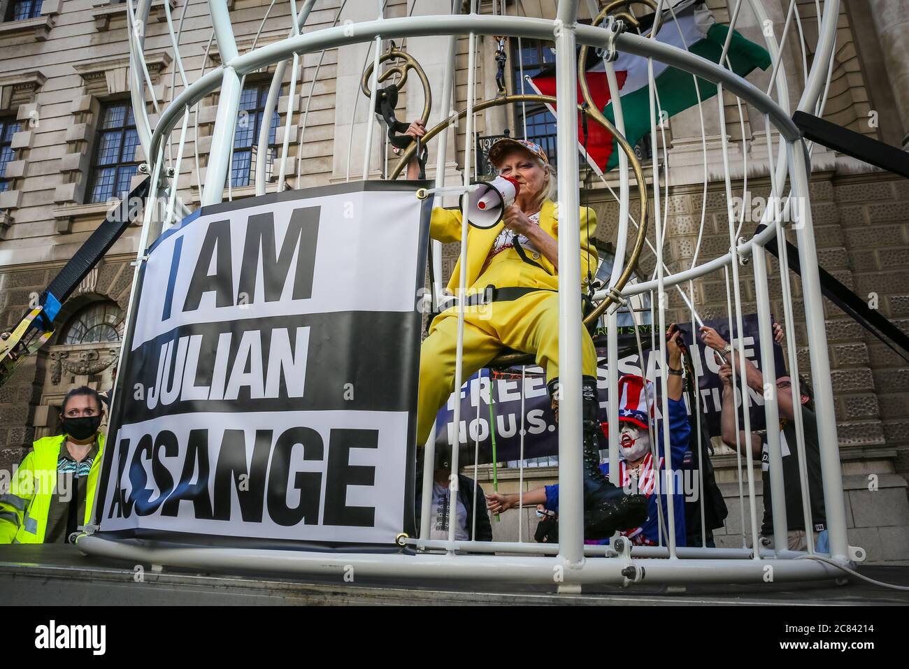 Londres, Reino Unido, 21 de julio de 2020. Dame Vivienne Westwood está enjaezada en una jaula gigante con un signo de "Yo soy Julian Assange", y suspendido 10 pies en el aire frente a la Corte Penal Central de Old Bailey, en protesta por la extradición de Julian Assange por los Estados Unidos. Westwood está vestido con un traje de pantalón amarillo, que enfigura la metáfora de la mina de carbón de Canarias, para ilustrar que Assange está siendo sacrificado. Más tarde se presenta frente al Viejo Bailey con su mensaje. Crédito: Imageplotter/Alamy Live News Foto de stock