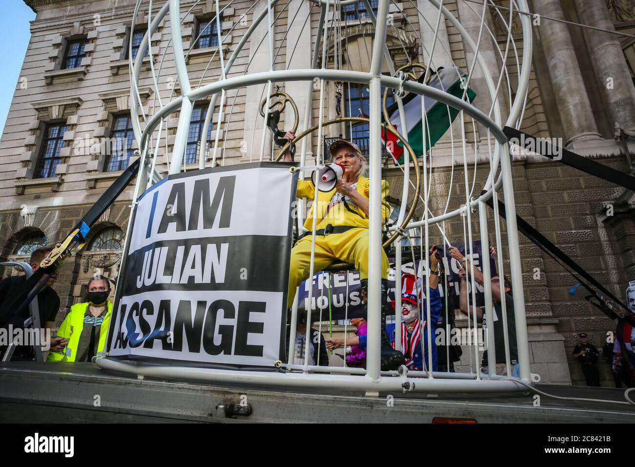 Londres, Reino Unido, 21 de julio de 2020. Dame Vivienne Westwood está enjaezada en una jaula gigante con un signo de "Yo soy Julian Assange", y suspendido 10 pies en el aire frente a la Corte Penal Central de Old Bailey, en protesta por la extradición de Julian Assange por los Estados Unidos. Westwood está vestido con un traje de pantalón amarillo, que enfigura la metáfora de la mina de carbón de Canarias, para ilustrar que Assange está siendo sacrificado. Más tarde se presenta frente al Viejo Bailey con su mensaje. Crédito: Imageplotter/Alamy Live News Foto de stock