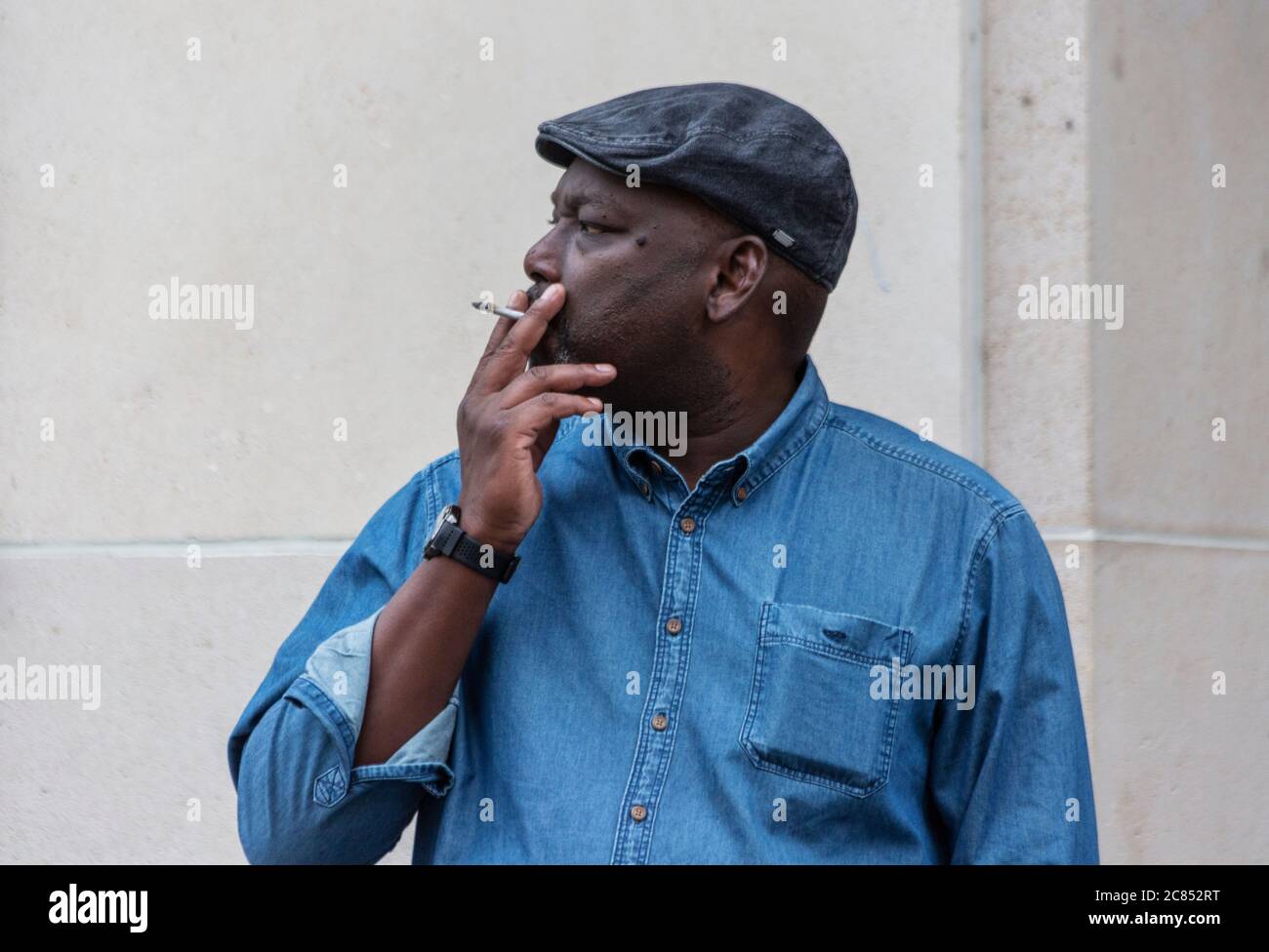 Retrato de un hombre negro fumando en una calle Foto de stock