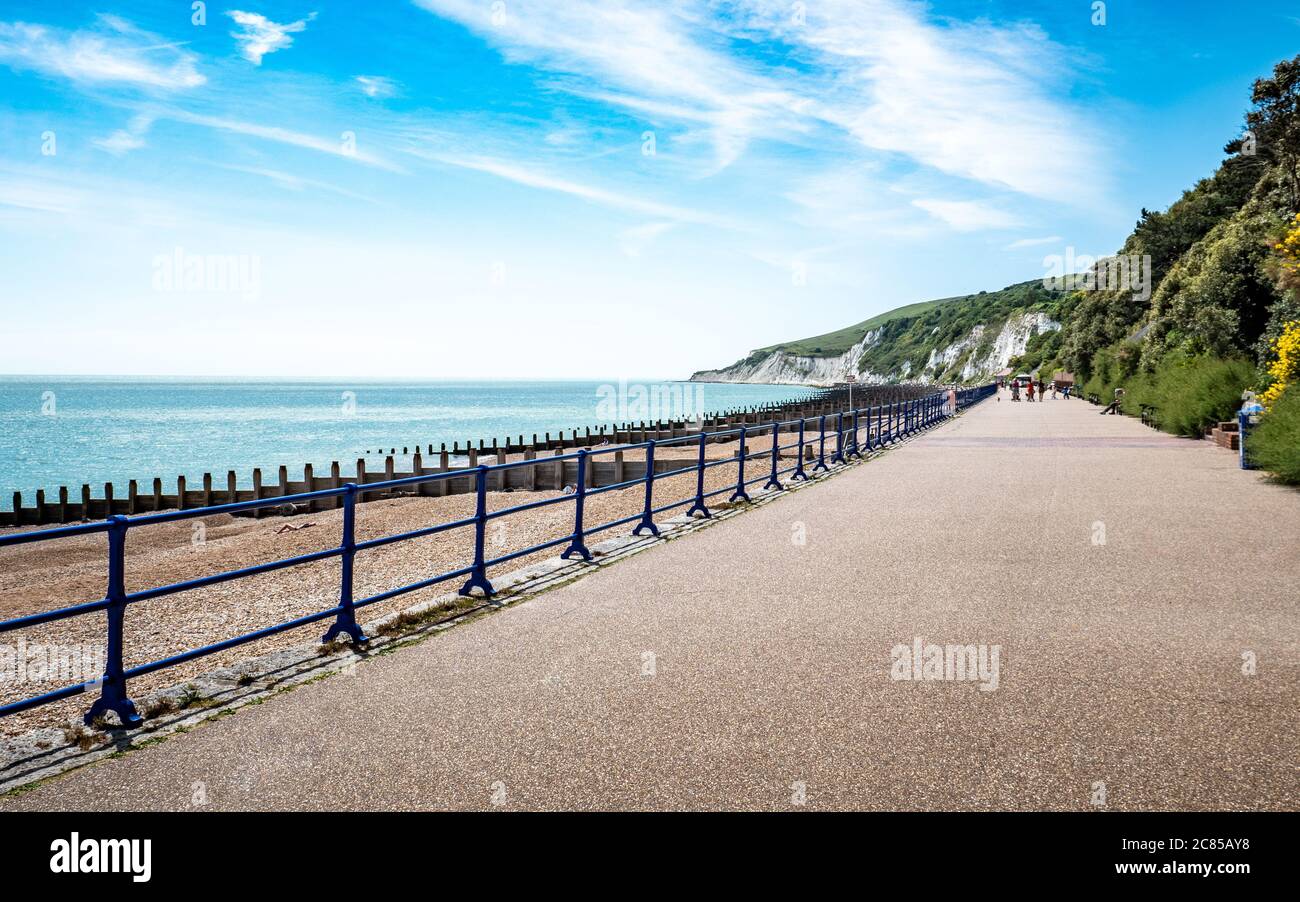 Eastbourne Promenade, East Sussex, Inglaterra. Una vista luminosa del verano al oeste a lo largo del mar hacia los acantilados de tiza blanca y South Downs. Foto de stock