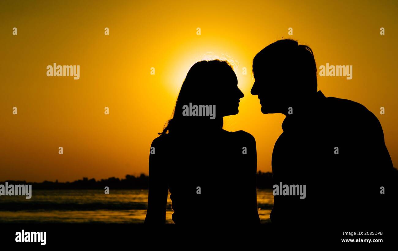 Pareja joven enamorada se encuentra con el amanecer (puesta de sol) en las orillas del río. Foto de stock