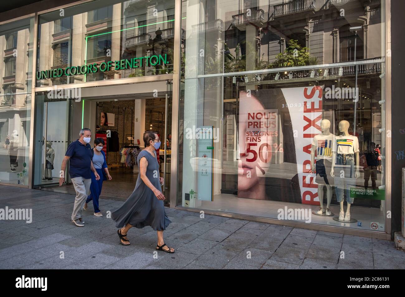 Barcelona, Cataluña, España. 21 de julio de 2020. Personas que pasan por  las ventanas de la tienda con promociones de ventas de hasta el 50% de la  tienda United Colors de Benetton