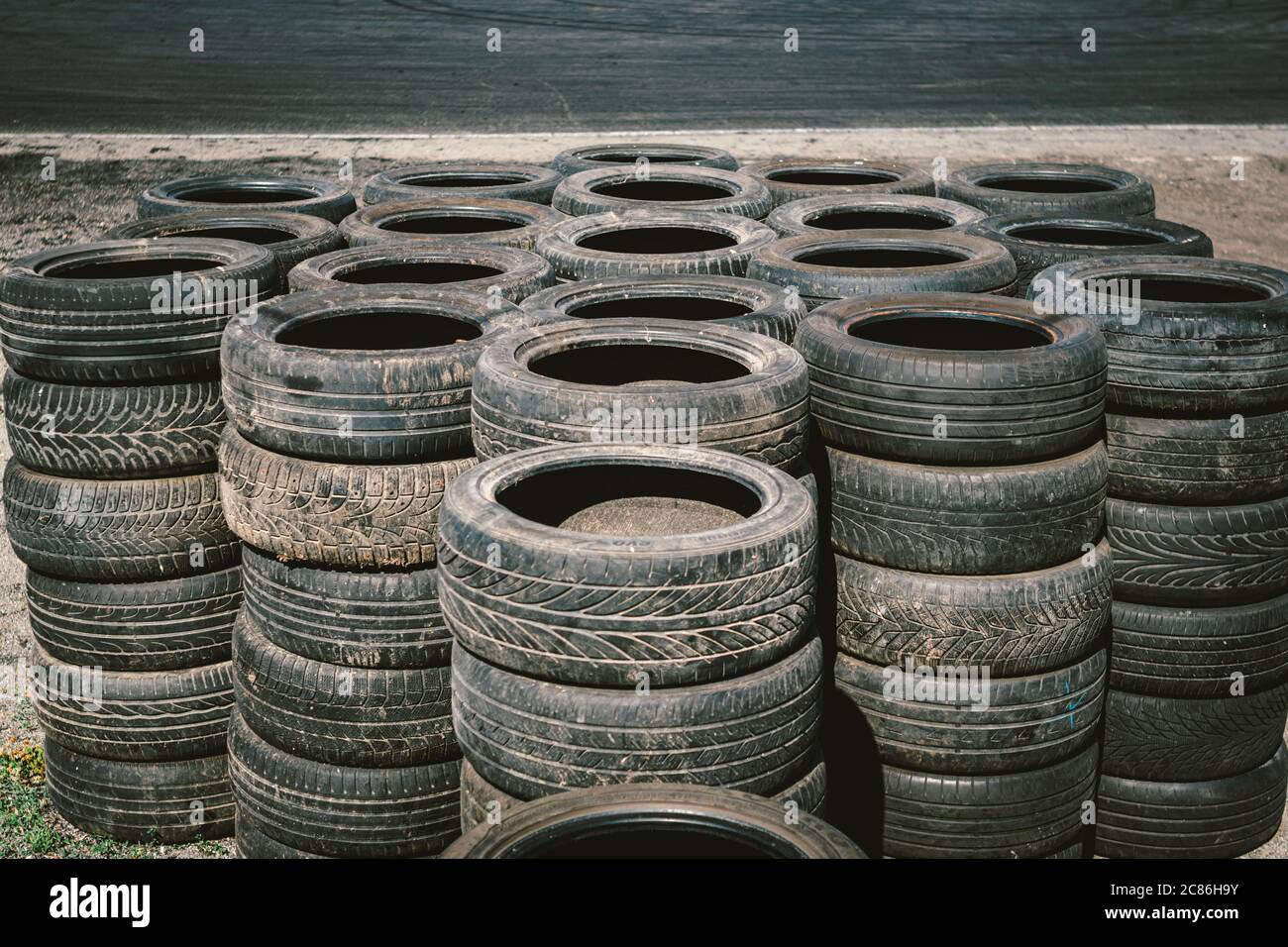 Muchos viejos neumáticos usados de coche apilados uno encima del otro en el  complejo deportivo del automóvil. Vertedero industrial para el tratamiento  de neumáticos de desecho y caucho Fotografía de stock -
