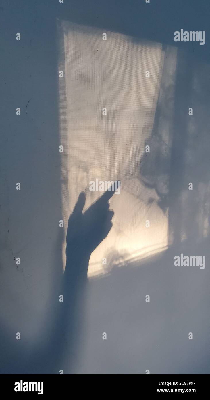 Sombras borrosas de la silueta de la mano con el índice en la proyección de la ventana y parece un gesto de mano fantasma. Concepto de Halloween Foto de stock