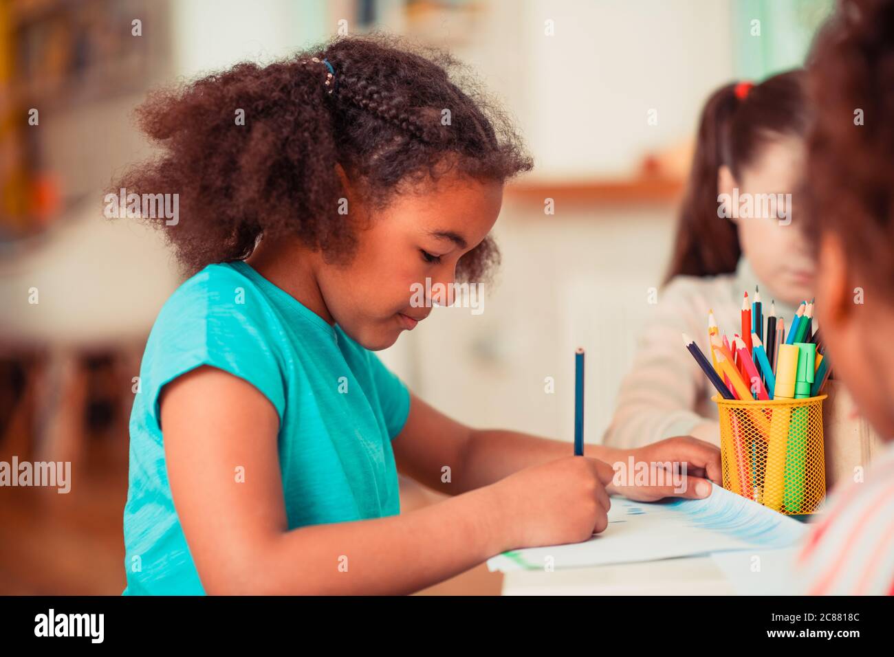 Dibujo de chica con un lápiz azul durante la clase de arte Foto de stock