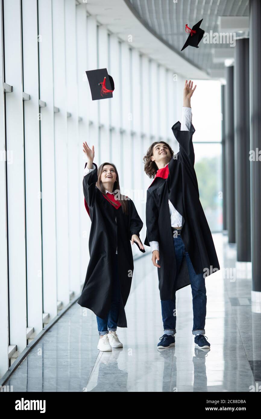 El hombre y la mujer graduados que lanzan sombreros de graduación en el  aire, feliz pareja de estudiantes en el día de graduación están lanzando  sombreros de graduación y la celebración de