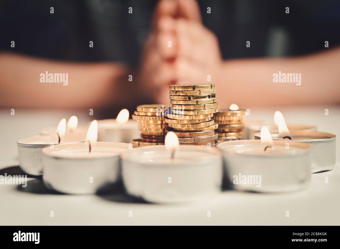 Manos de un hombre orando con un círculo de ardor velas con una pila de  monedas en el interior Fotografía de stock - Alamy