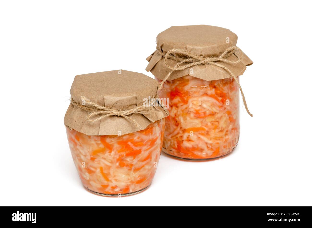Dos tarros de cristal de sauerkraut casero con zanahoria sobre fondo blanco. Alimentos fermentados y encurtidos caseros. Probiótico natural. Alimentación y dieta saludables Foto de stock