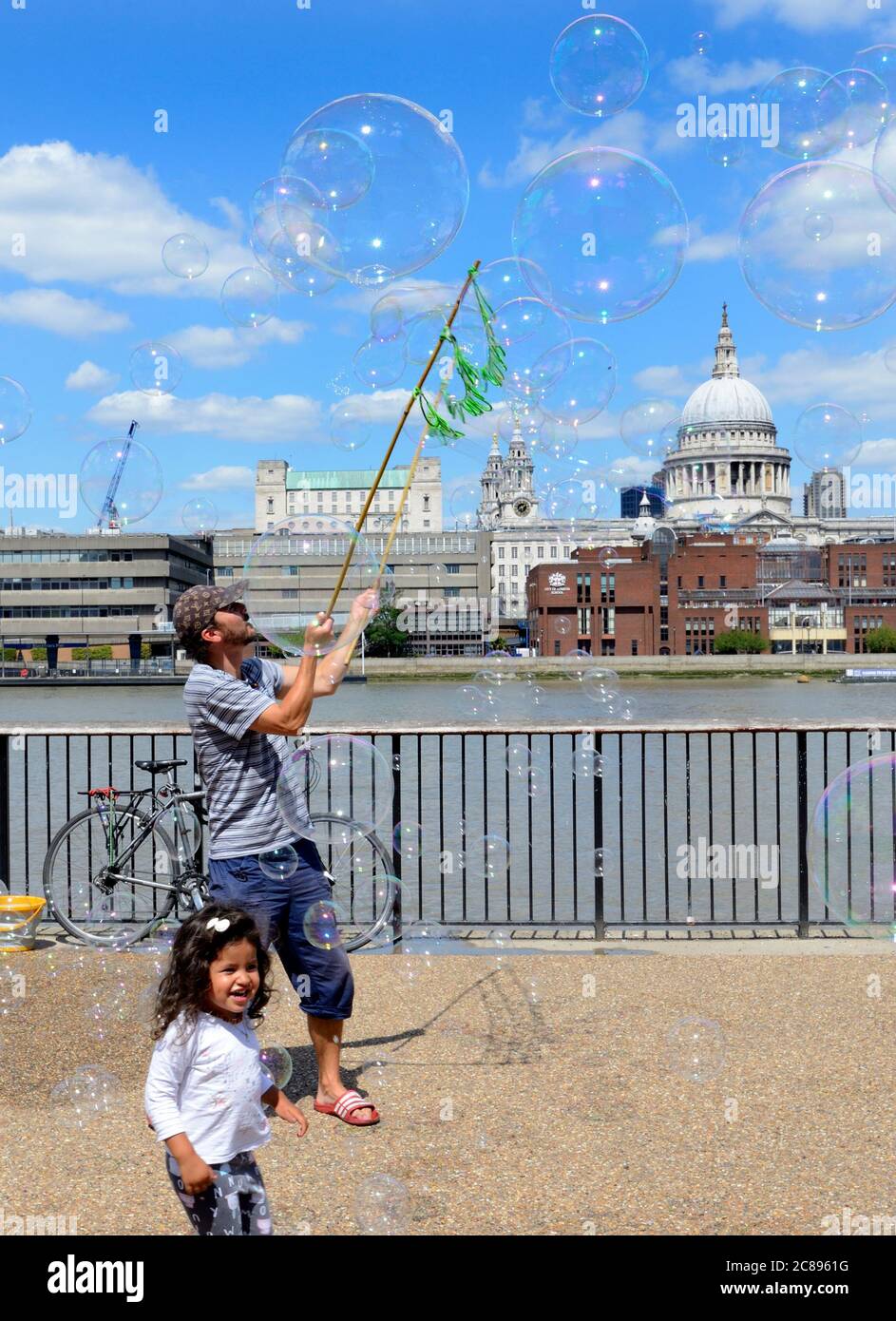 Londres, Inglaterra, Reino Unido. Street animainer en la orilla sur soplando burbujas para que los niños persigan Foto de stock