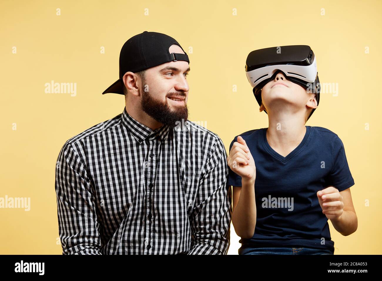 Hijo adolescente utiliza gafas de realidad virtual cerca de padre barbudo. Concepto de tecnología futura Foto de stock