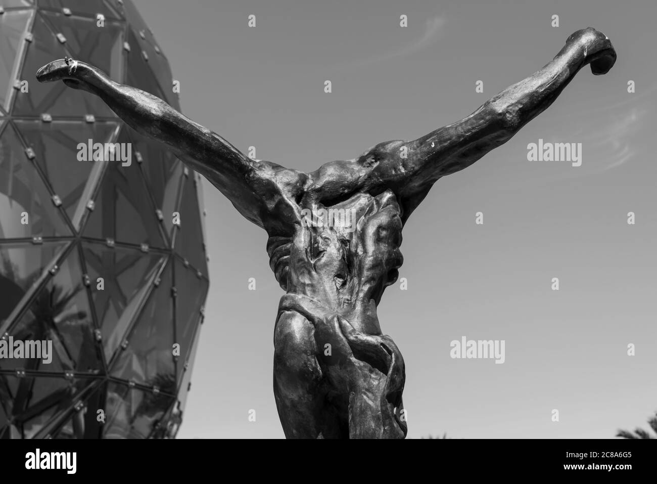 Foto en blanco y negro de la parte posterior deformada de la escultura de metal Representando a Jesús de pie como en la cruz Foto de stock