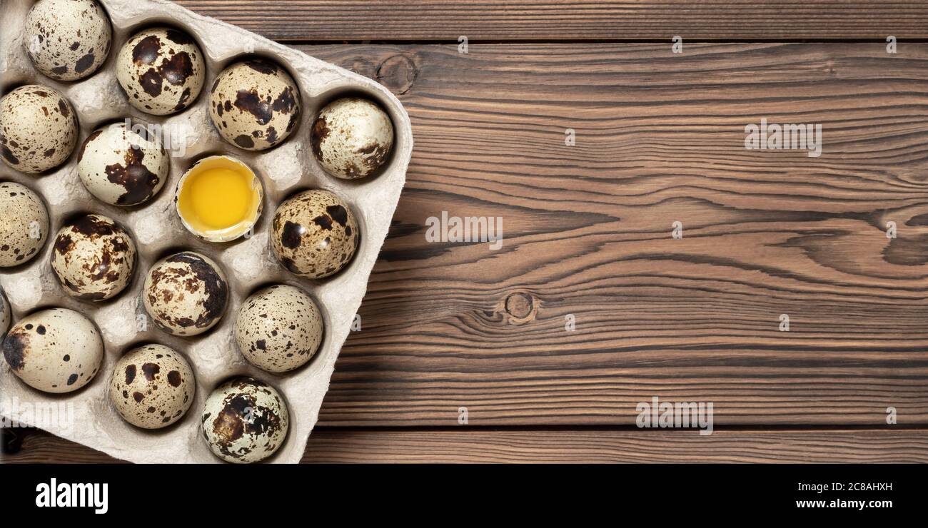 Codornices huevos en cartón sobre una mesa de madera, espacio de copia, banner horizontal Foto de stock