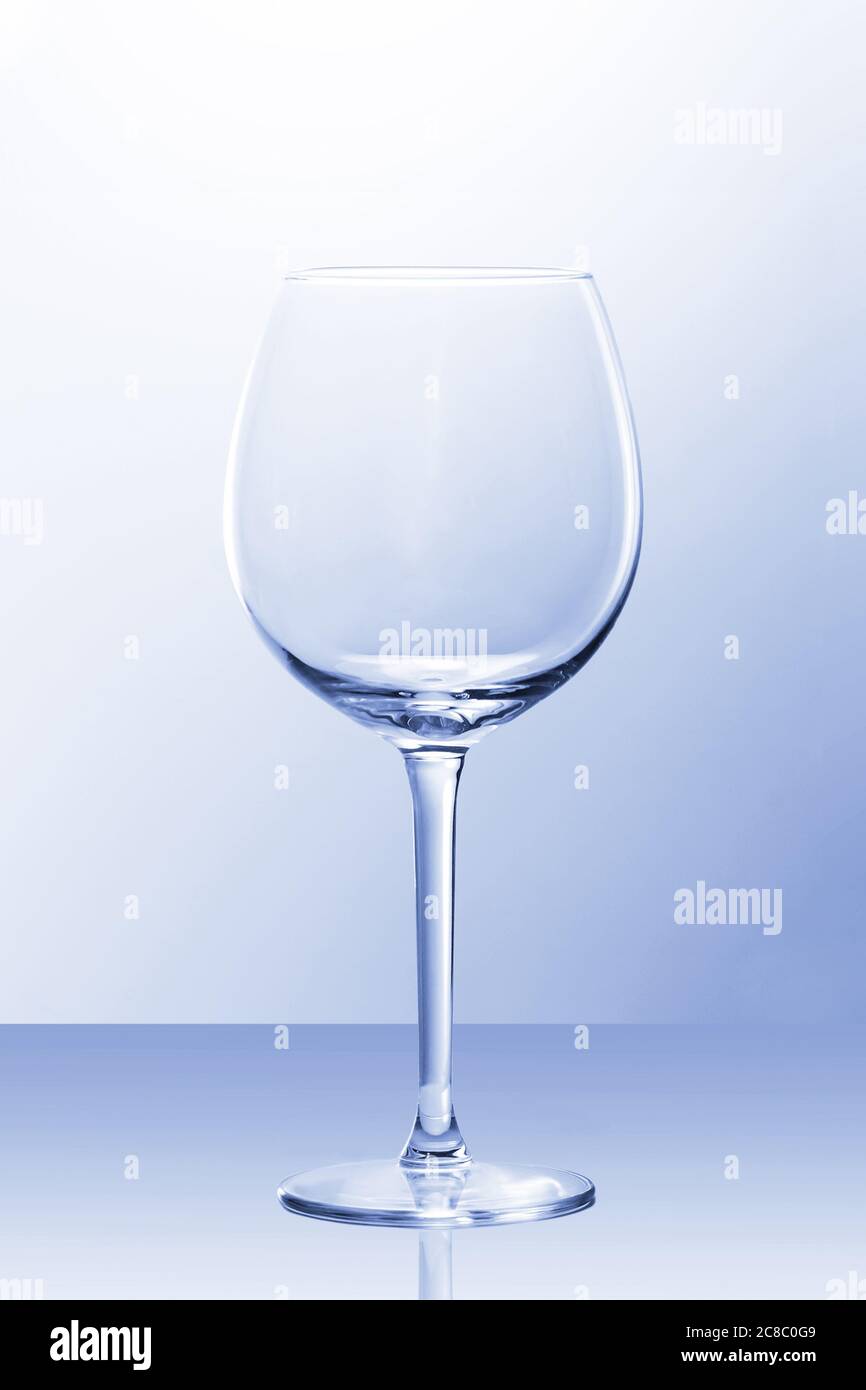 Una copa de vino tinto vacía con luz ligeramente azul y un reflejo de POV Foto de stock