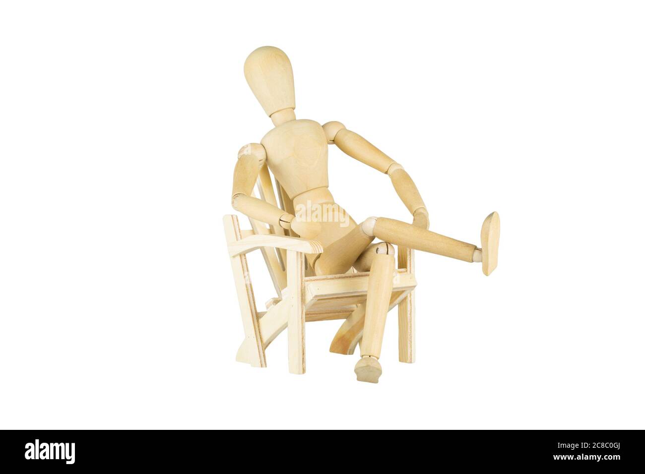 Una muñeca de madera está sentada en una silla de madera en miniatura sobre fondo blanco Foto de stock