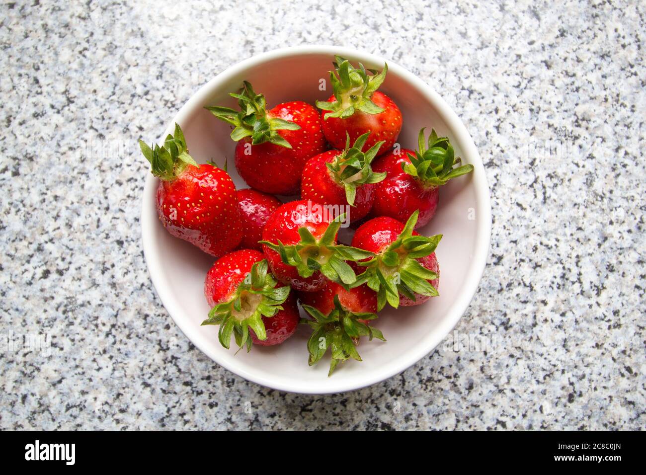 Fresas en un cuenco en una mesa desde arriba Foto de stock