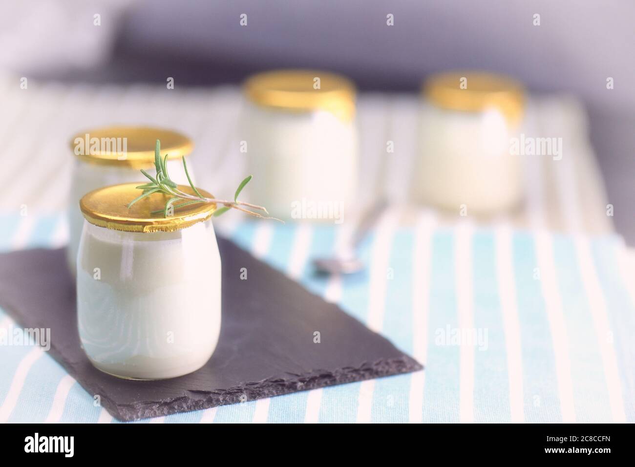 Yogur en un tarro de vidrio con una cuchara. Alimentos saludables para el desayuno, productos lácteos Foto de stock