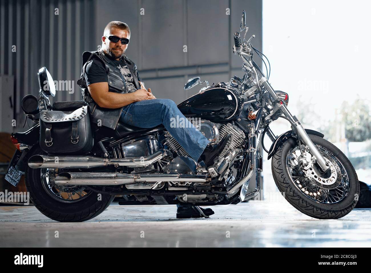 Motociclista barbudo con ropa de negro con moto Fotografía de stock -
