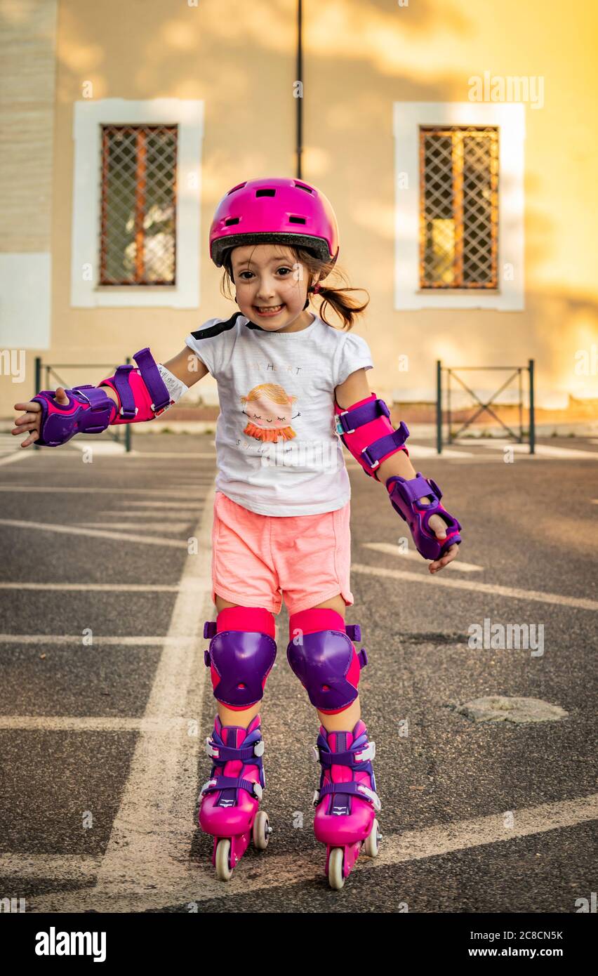 Una niña aprende a deslizarse por la calle de la ciudad. Seguro con casco y  protecciones para codos, muñecas y rodillas. Conceptos: Diversión, s  Fotografía de stock - Alamy
