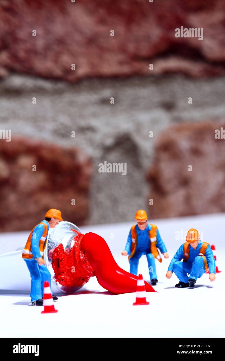 Figura miniatura personas investigando un derrame de tubos de pintura roja de artistas Foto de stock