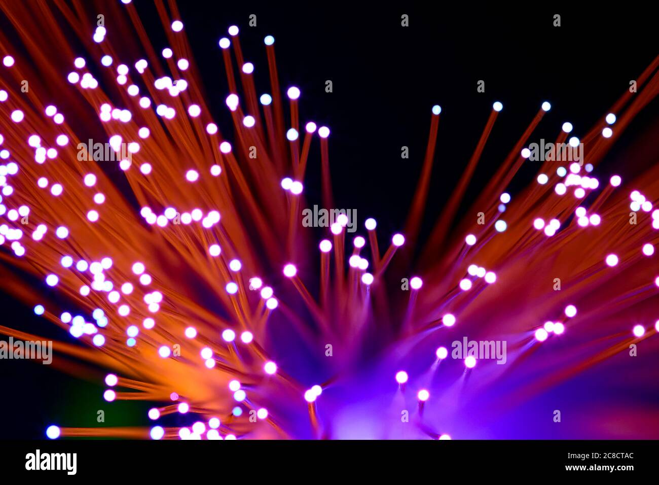 Filamentos de fibra óptica con luz que pasa a través de la creación de una colorida explosión abstracta de patrón de luz Foto de stock
